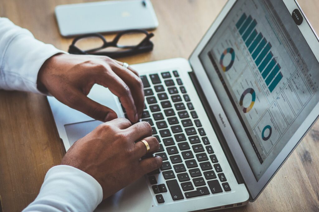 Mains d'homme tapant sur le clavier d'un un PC dont l'écran affiche des statistiques.